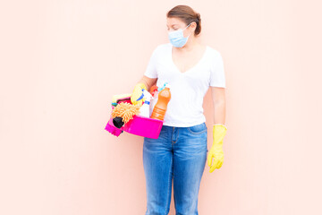 caucasian woman holding basin with cleaning supplies