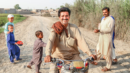 a farmer is riding a bike and feeling happy in a village - obrazy, fototapety, plakaty