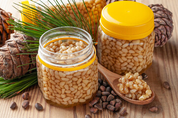 Pine nut with honey in a transparent jar. The jar is open. Nearby is a wooden spoon with honey and...