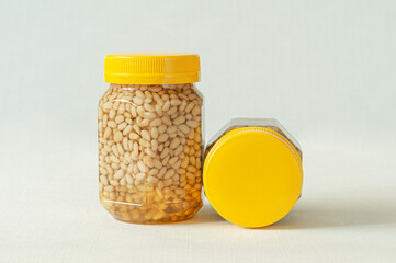 Pine nut with honey in a transparent jar with a yellow lid. A smaller jar with nuts and honey is...
