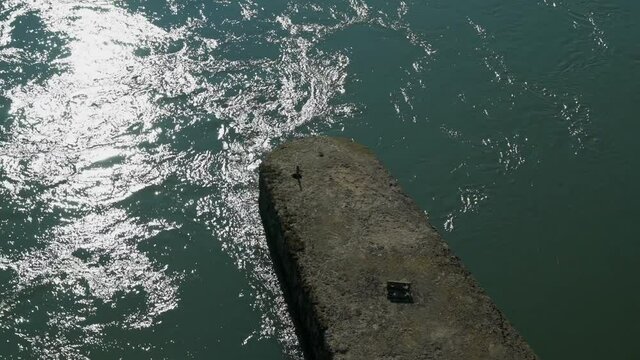 An old weathered stone pier covered in lichen on the sea in 4K