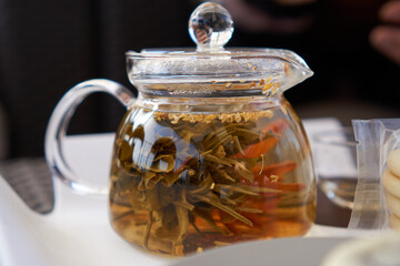 Flower tea in transparent tea pot and chocolate cookies