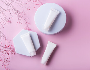 White tubes of cream on a pink background