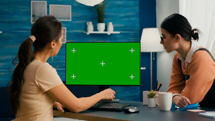 Two friends sitting in front of mock up computer green screen chroma key. Business woman working at...