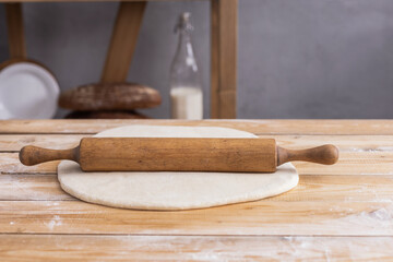 Wheat dough at flour powder and rolling pin on table for bread cooking or baking. Pizza dough