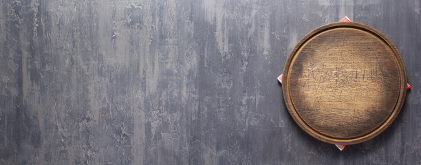 Pizza cutting board and cloth napkin on stone surface of table. Food recipe concept at tabletop or wall background