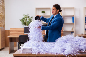 Young male employee and a lot of cut papers in the office