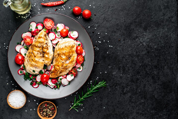 Grilled chicken breast and salad with fresh vegetables, tomatoes and radishes. Chicken meat with salad. Healthy food on stone background with copy space for your text
