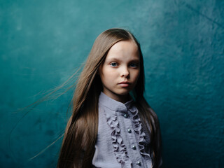 Portrait of a girl in a gray sundress on a turquoise background close-up of her loose hair