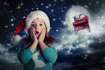 Cute little child and Santa Claus flying in his sleigh on background. Christmas celebration