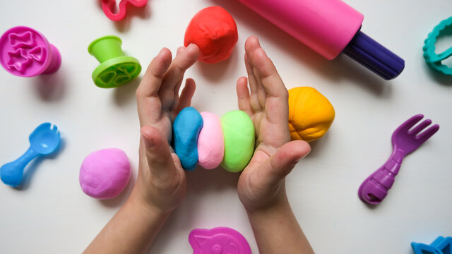 Children's hands play with plastic multi-colored mass. Modeling and development of fine motor skills.