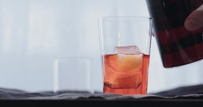 Slow motion making cocktail aperetivo in tumbler glass with window on background