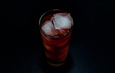 A glass filled with a red cocktail and full of ice cubes.