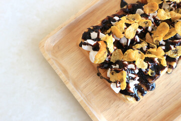Toasts bread with cornflakes and chocolate on white wooden table