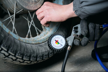 A worker is inflating a motorbike wheel by the car tyre inflating gun close up.