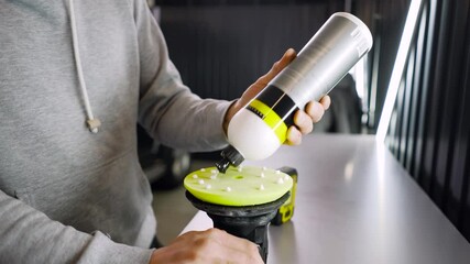 Professional worker man applying a polishing paste or car wax for polish car with a polish machine at car workshop close-up. Auto service industry.