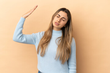 Fototapeta premium Young caucasian woman isolated on beige background with tired and sick expression