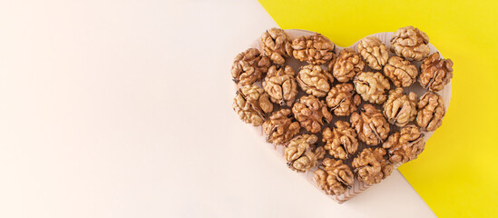 Organic walnuts are shaped like a heart on a minimal background. Healthy food for the heart, useful microelements and vitamins. Healthy Concept. Useful snack for vegetarians and more.