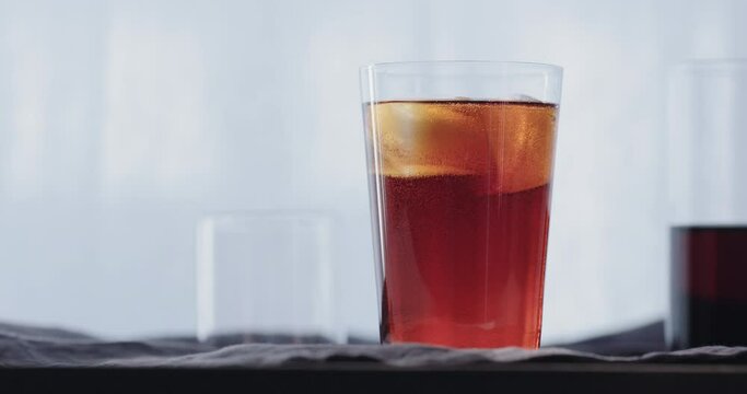 Slow motion cocktail aperetivo in tumbler glass with window on background