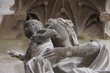 Stone sculpture of an energetic Madonna with child in a type of stone that makes it nearly appear...