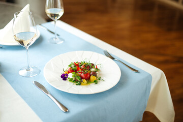 Gourmet peeled tomatoes salad on the table with a glass of white wine