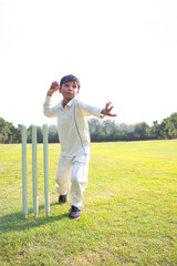 Young boy bowling leg spin in a cricket