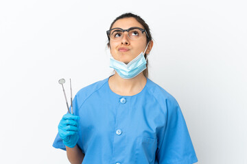 Young woman dentist holding tools isolated on white background and looking up