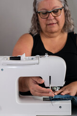 Close-up of a sewing machine with a woman unsupported in the background