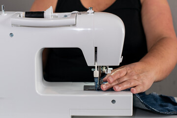 Close-up of a sewing machine with a woman unsupported in the background