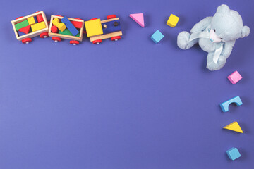 Baby kids toys background. Wooden train, blue teddy bear and colorful blocks on navy blue background
