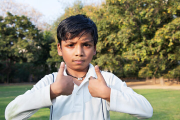 A boy in cricket uniform and pointing