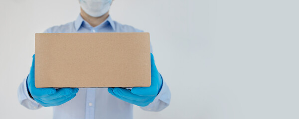 Delivery man holding cardboard boxes in medical gloves protective mask on white background. copy space. Fast and free Delivery transport . Online shopping and Express delivery . Quarantine. Banner 