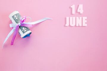 calendar date on pink background with rolled up dollar bills pinned by pink and blue ribbon with copy space. June 14 is the fourteenth day of the month