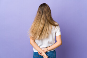 Young woman over isolated purple background in back position and looking back