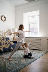 Young mother with little daughter practicing yoga at home. Family fizical activity, sporty mom and kid