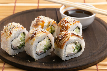 sushi, rolls on a plate with chopsticks, on a wooden background	