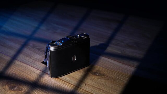 An old retro camera on a wood background in the studio with window light.