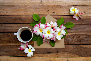 hot coffee espresso with colorful flowers frangipani in envelope arrangement flat lay postcard style on background wooden