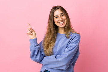 Young woman over isolated pink background happy and pointing up