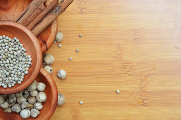 pepper, cardamom, and cinnamon in a wooden bowl on a wooden tray. close up with selective focus