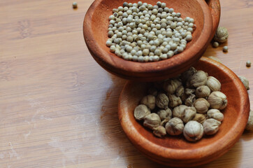 pepper, cardamom, and cinnamon in a wooden bowl on a wooden tray. close up with selective focus