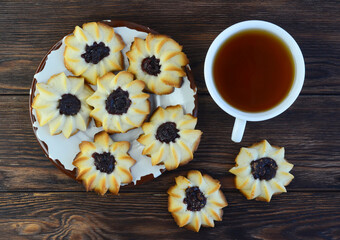 homemade shortbread cookies kurabye and a cup of tea on a textured wooden table top view