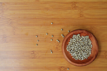 pepper in a wooden bowl on a wooden tray. close up with selective focus