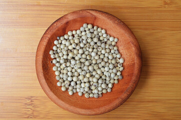 pepper in a wooden bowl on a wooden tray. close up with selective focus