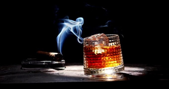 Glass of whiskey and smoking cigar on table. Slow motion, copy space, black background. Whiskey, brandy, cognac, alcoholic drink .