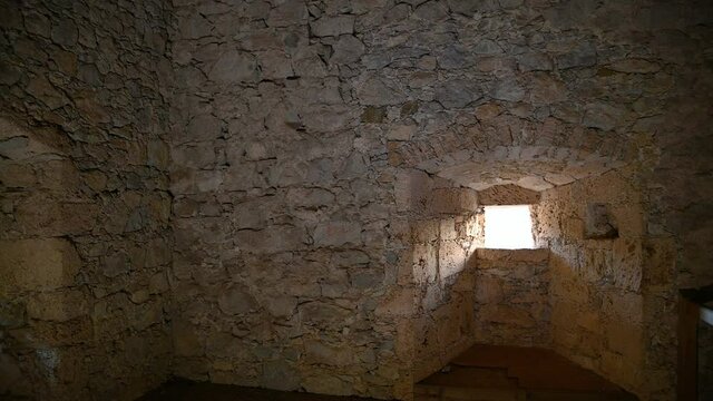 Interior view of ancient tower in castle Kamen, Slovenia. Wooden floor and old stone thick walls. Inside of middle age fortified watchtower. Artificial light. Right pan, wide angle
