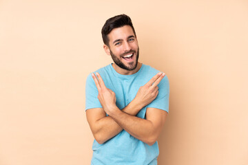 Caucasian handsome man isolated on beige background smiling and showing victory sign