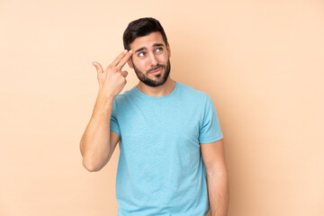 Fototapeta premium Caucasian handsome man isolated on beige background with problems making suicide gesture