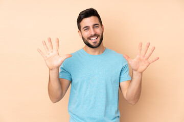 Fototapeta premium Caucasian handsome man isolated on beige background counting ten with fingers