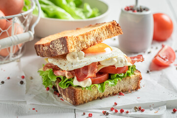 Crunchy sandwich with egg, bacon and tomato. British breakfast.